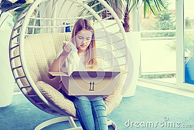 Girl sitting in chair and opening a package Stock Photo