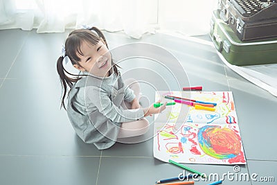 Girl sitting on the floor and drawing picture by crayon Stock Photo