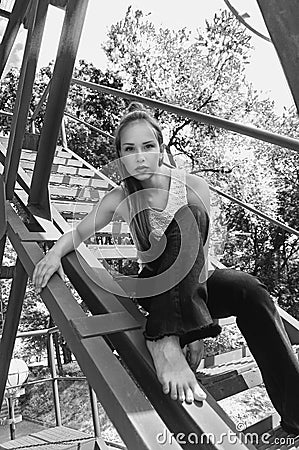 Girl sitting on an iron stairs. Stock Photo