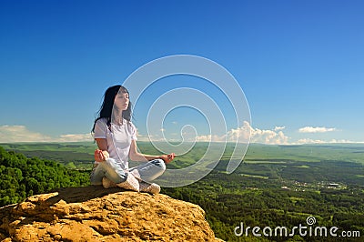Girl sitting in the lotus position on the mountain Stock Photo