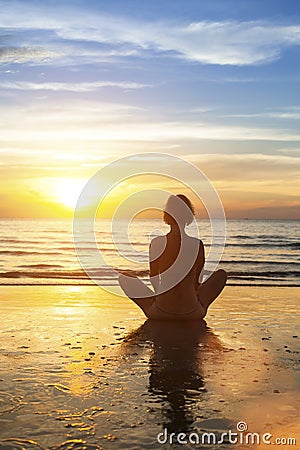 Girl sitting meditation on the ocean during an amazing sunset. Stock Photo