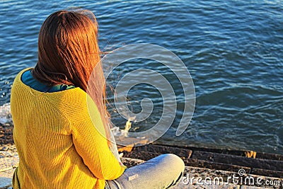 Girl sitting next to the riverbank at sunset in Lisbon Editorial Stock Photo