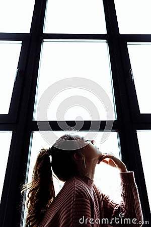 Girl is sitting opposite the window. The girls hair is pulled back in a ponytail Stock Photo