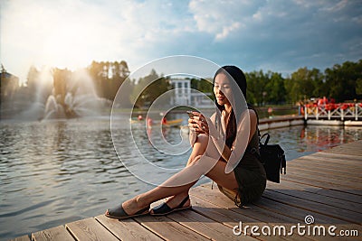 Girl sitting on pier and looking at the river Stock Photo