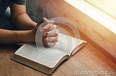 Girl sitting and praying for blessings from god With the Bible folded hands in biblical spiritual and religious prayer, Stock Photo
