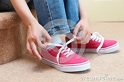 Girl Sitting On Stairs And Tying Shoelaces Stock Photo