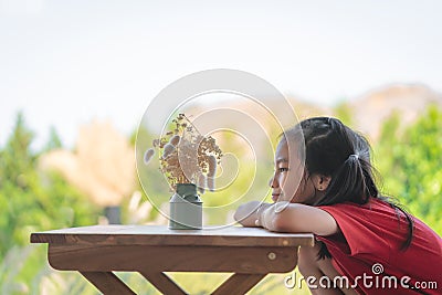 Girl sitting table with a jar of flower for children love nature concept Stock Photo