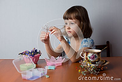 Girl sitting at the table and weaving beadwork Stock Photo