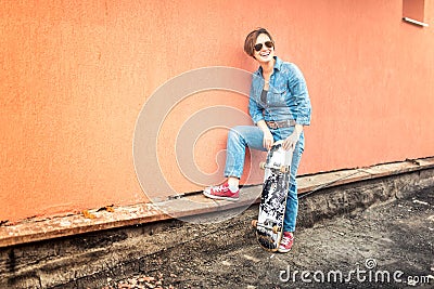 Girl with skateboard and sunglasses living an urban lifestyle. Hipster concept with young woman and skateboard, instagram filter Stock Photo