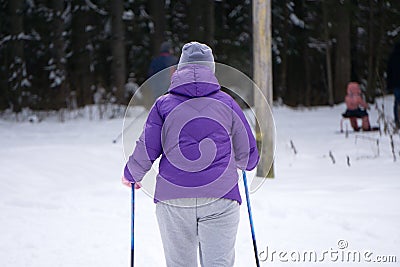 Girl skiing during snowfall weather ski resort Skier wears a blue winter coat, purple hot pants, blue shorts and white gloves. The Editorial Stock Photo