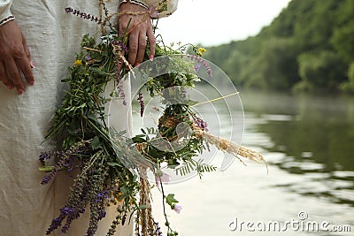 The girl in Slavic clothes with a wreath on the background of the river Stock Photo