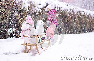 Girl sledding her sister in snow park. Family vacation in winter. Stock Photo