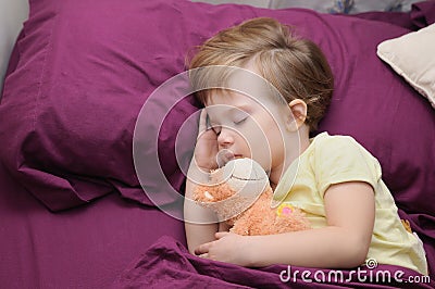 Girl sleeping peacefully with her teddy bear on the bed Stock Photo