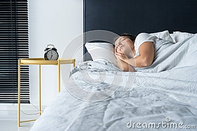 The girl sleeps next to the alarm clock. Time to wake up. On the wake-up clock 7 a.m. Deep sleep Stock Photo
