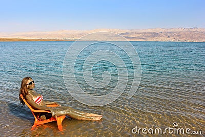 Girl smeared with therapeutic mud sunbathes, Dead Sea Stock Photo