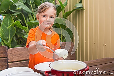 Girl with a smile imposes semolina his plate Stock Photo