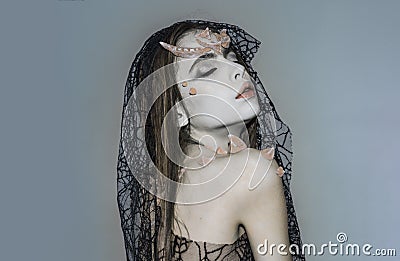 Girl with smokey eyes with thorns on skin wearing dark veil, Black Widow costume. Woman in dress with spider net pattern Stock Photo