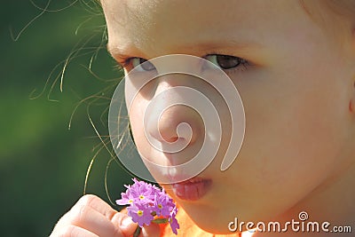 Girl sniffs a lilac bunch of flowers puffy lips serious look Stock Photo
