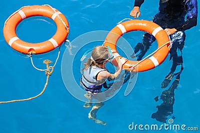 A girl in a mask with an instructor holds on to a lifebuoy Editorial Stock Photo