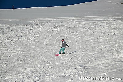 a girl on a snowboard rides down the side of the mountain Stock Photo