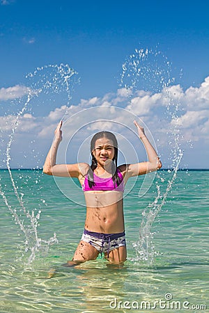 Girl splashing in the water at the beach Stock Photo