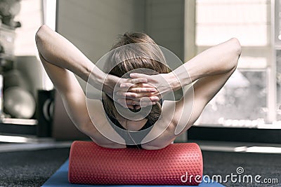Girl with sporty physique makes myofascial release of the back with foam roller. Roller for physiotherapy Stock Photo