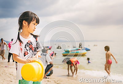 Girl is standing in busy beach looking out to the ocean. Stock Photo