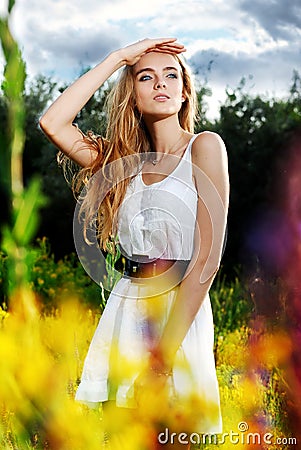 Girl standing on a flower glade and looks in Stock Photo