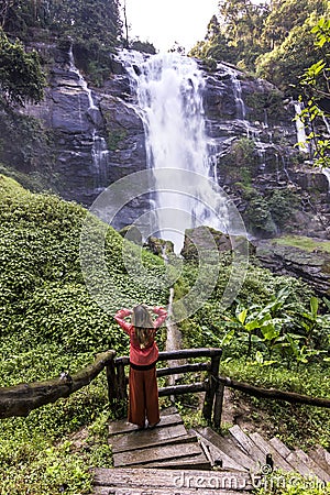 Girl standing in forest near huge waterfall in jungle of thailand Stock Photo