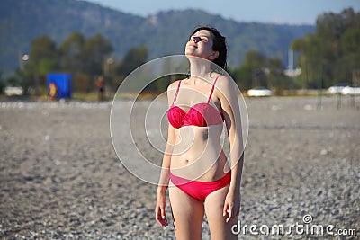 Girl standing on a pebble beach Turkey, face to sun Stock Photo