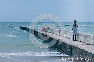 Girl standing on the sea pier in cold season Stock Photo