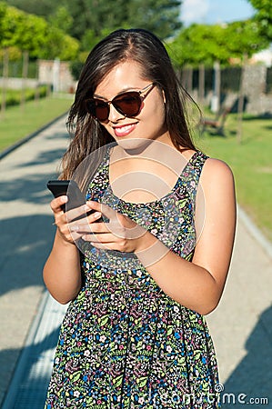 Girl standing and texting on telephone outside Stock Photo