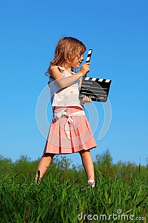 Girl stands in field with clapperboard in hands Stock Photo