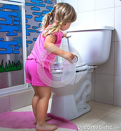 Girl the child is standing at the toilet with toilet paper in hands Stock Photo