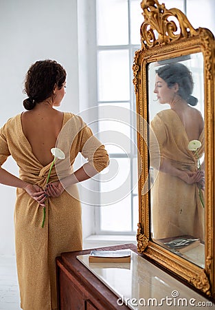 Vertical photo of a young brunette in a light dress with open back Stock Photo