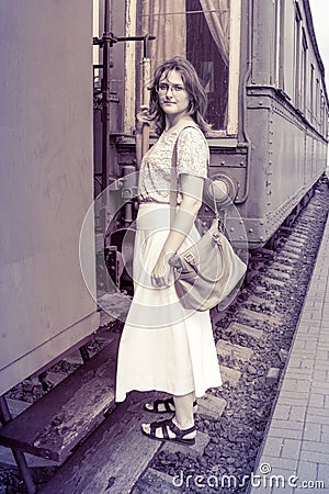 A girl stands on the steps of the cars train. Historical monochrome photo of a woman on the footboard of the car. The vintage Stock Photo