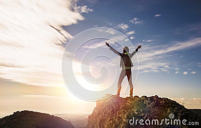 The girl stands on top of the mountain and enjoys the view of the valley. Stock Photo