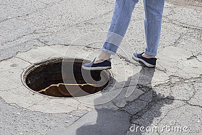 The girl steps into the open sewer hatch Stock Photo