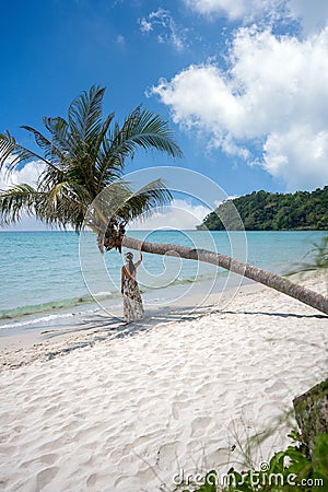 The girl stood back, standing under a coconut tree with bent trunks Stock Photo