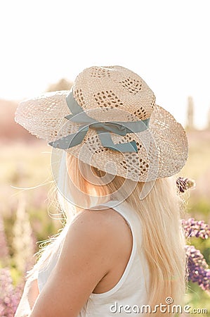 Girl in a straw hat turned to the field Stock Photo