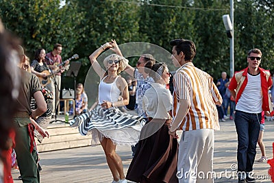 Moscow, Russia, September 08, 2018: girl in striped lush skirt dancing rock and roll on the dance floor with a man in Gorky Park Editorial Stock Photo