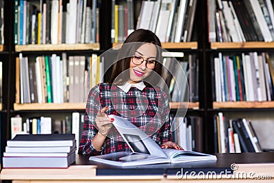 Girl student with glasses reading books in the library Stock Photo