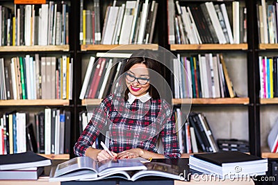 Girl student with glasses reading books in the library Stock Photo