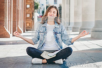 Girl student sitting on the floor and meditating. Girl prays in lotus position Stock Photo