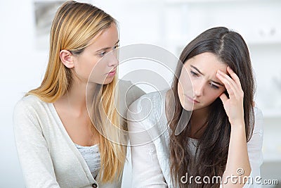 Girl supporting depressed female friend indoors Stock Photo