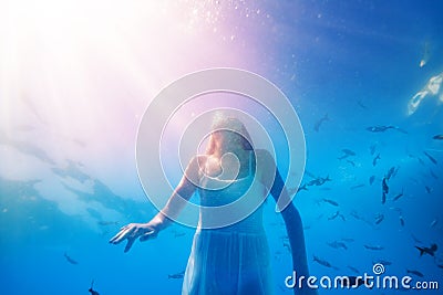 Girl swim underwater with fish school, wear dress Stock Photo