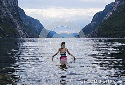 Girl swimming in the Lysefjord fjord from the village of Lysebotn. Stock Photo