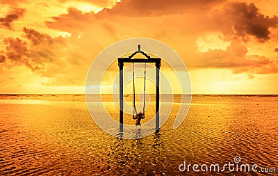 A girl on a swing over the sea at sunset in bali,indonesia 7 Stock Photo