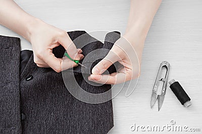 Girl tailor rips thread on a gray waistcoat. Stock Photo