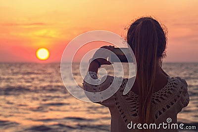 A girl takes a picture of the sunset Stock Photo